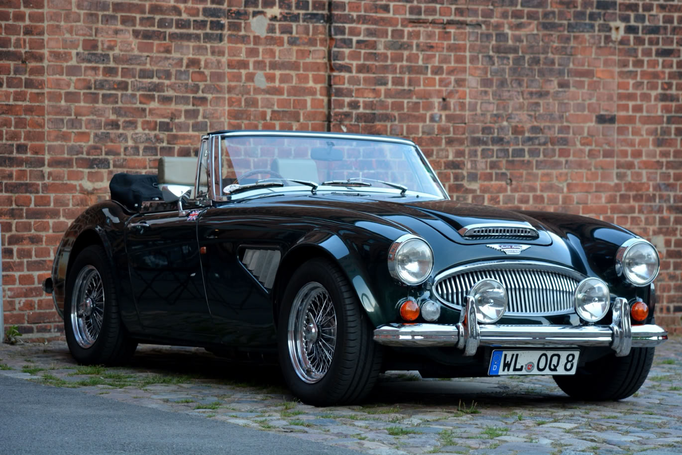 Ein schwarzes, klassisches Cabriolet steht vor einer Ziegelwand. wertvolle Oldtimer